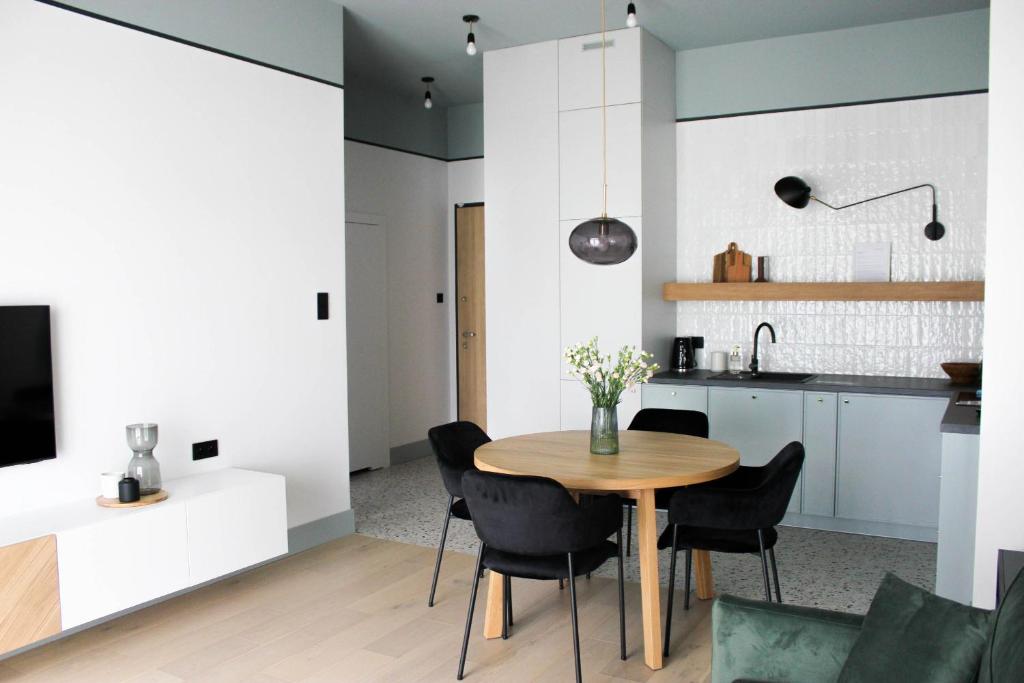 Il comprend une cuisine et une salle à manger avec une table et des chaises en bois. dans l'établissement Kwadrat Hallera, à Gdańsk