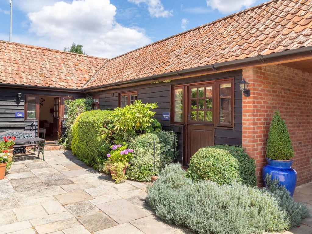 a brick house with a patio and bushes at Horseshoe in Little Glenham