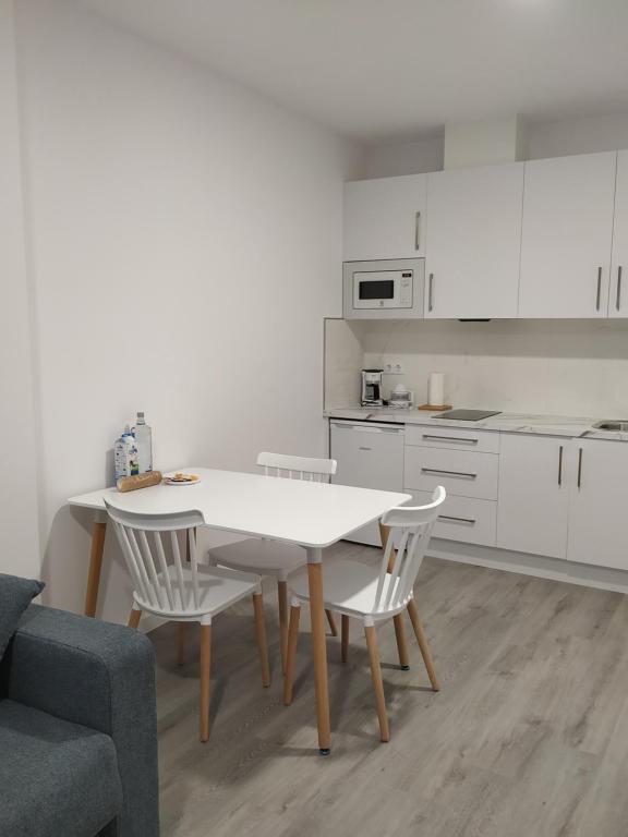 a white kitchen with a white table and chairs at GRUPOELE3 MUXIA PUERTO in Muxia
