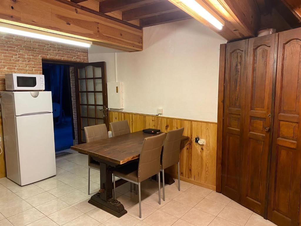 a kitchen with a wooden table and chairs and a refrigerator at Petit coin de paradis à 10 min de St-Girons in Montjoie-en-Couserans
