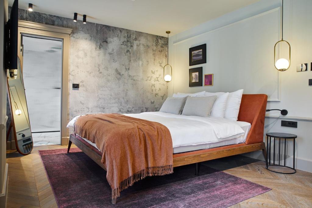 Martis Forum Heritage Hotel & Residence في بوريتش: غرفة نوم مع سرير كبير مع جدار اسمنتي