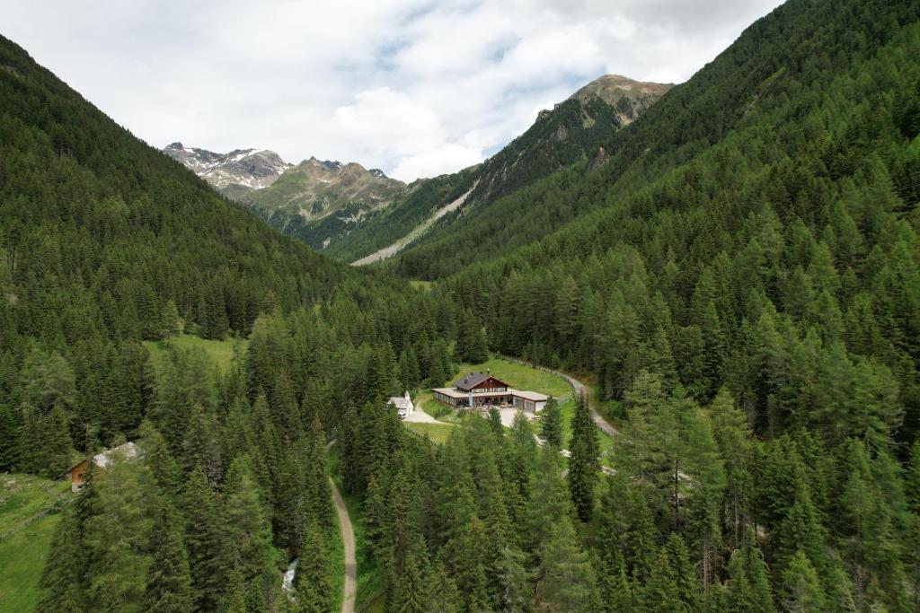 a house in the middle of a valley with trees at Badl im Mühlbacher Talile in Gais