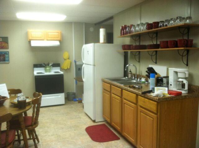 a kitchen with a sink and a refrigerator and a table at White Caps Motel in Port Clinton