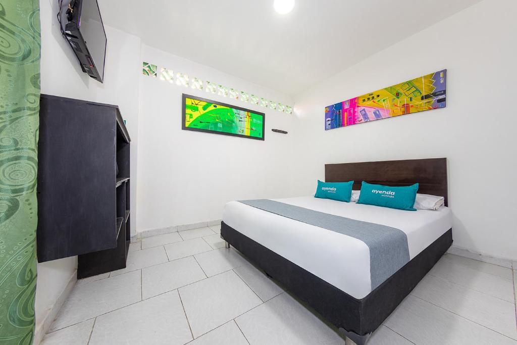 a bedroom with a large bed with blue pillows at Ayenda Villas de San Juan in Medellín