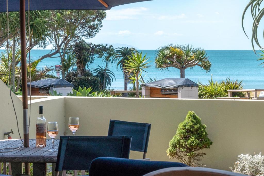 una mesa con copas de vino en un balcón con vistas al océano en The Sands Apartment 23 en Onetangi