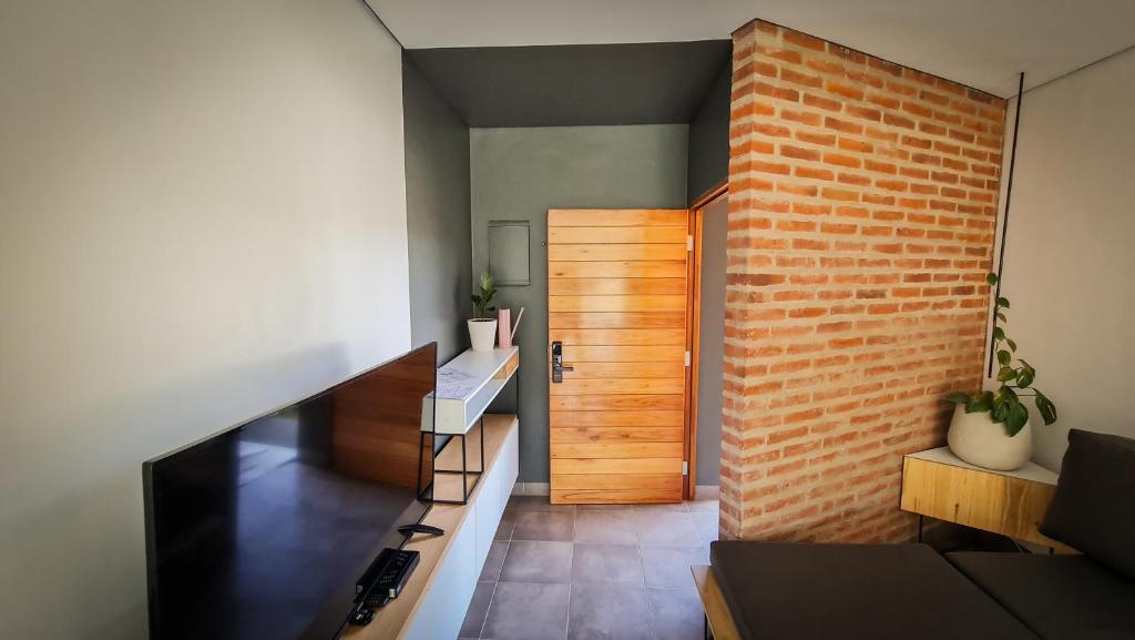 Casa D, moderna de 2 habitaciones con jardín en barrio privado في سان سلفادور دي خوخوي: غرفة بجدار من الطوب وباب خشبي