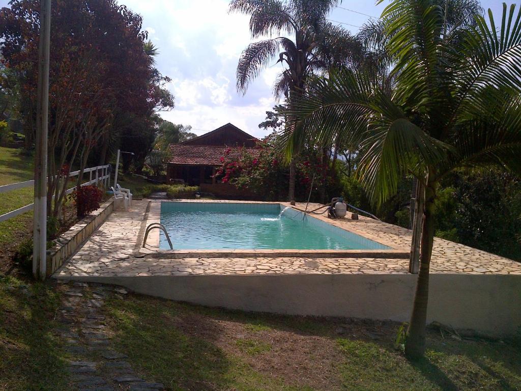 una piscina en un patio con una palmera en Pousada Céu de Luz, en Itapeva