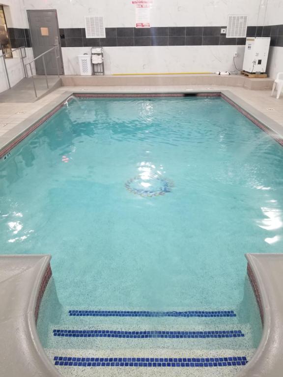 a swimming pool with blue water and stairs in it at Days Inn & Suites by Wyndham Webster NASA-ClearLake-Houston in Webster