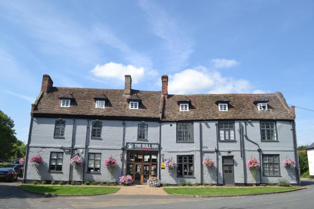 a large brick building with a clock on the front of it at The Bull Inn in Mildenhall