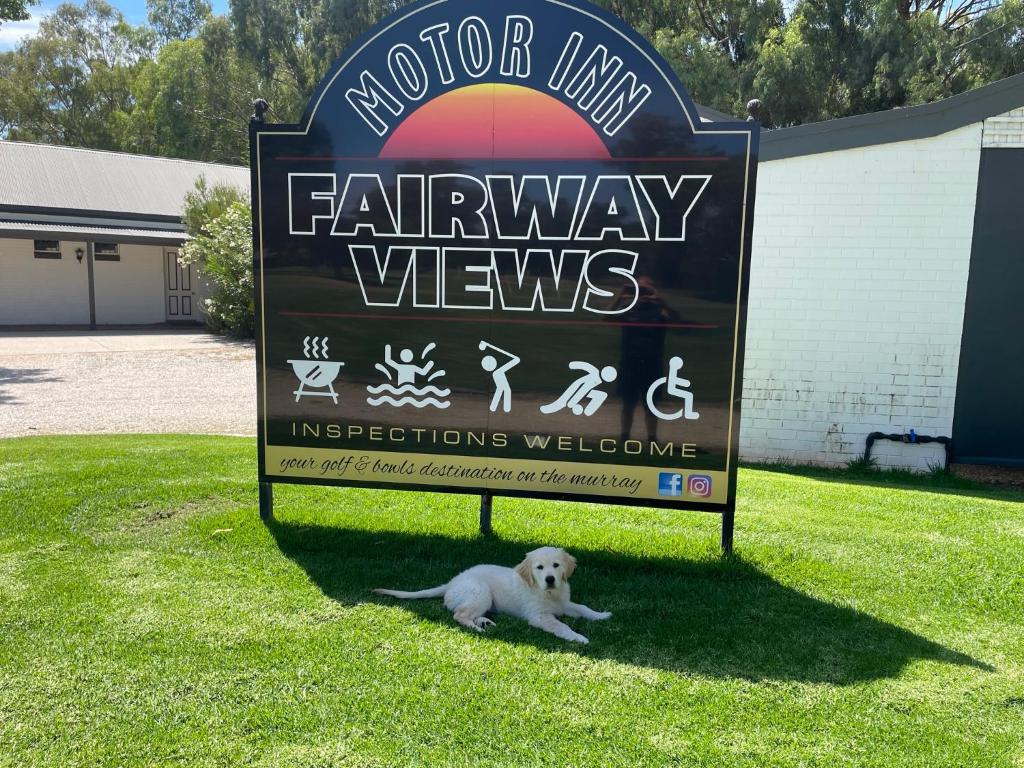 Ein Hund, der neben einem Schild für eine Fernsehshow liegt. in der Unterkunft Fairway Views Motor Inn in Tocumwal