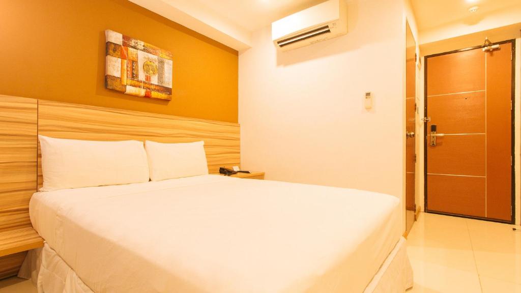 a bedroom with a white bed and a shower at Guijo Suites Makati - Quarantine Hotel in Manila