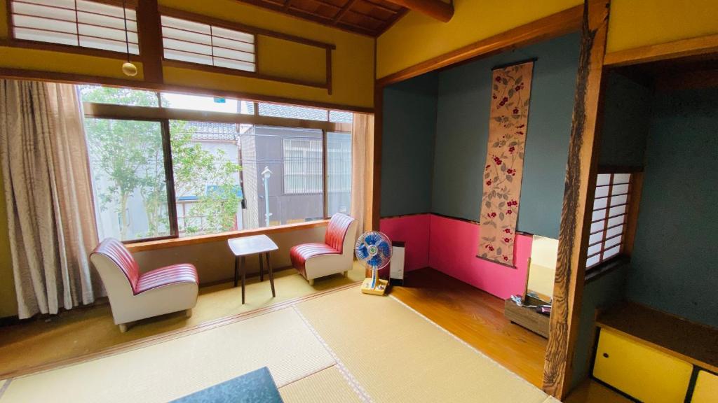 Habitación con sillas, mesa y ventana en ゲストハウス　華屋 (guest house HANAYA）, en Sado