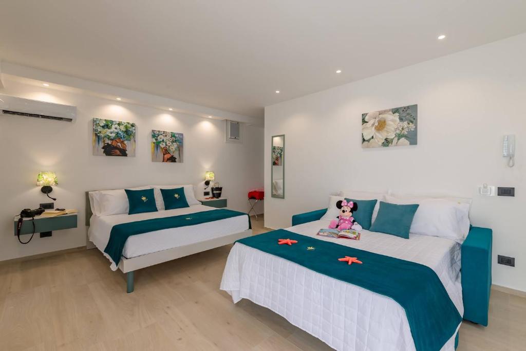 a bedroom with two beds and a doll sitting on the bed at Vittoria Luxury Rooms in Sciacca