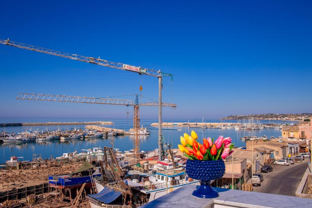 a vase of flowers on a ledge with a crane at Vittoria Luxury Rooms in Sciacca