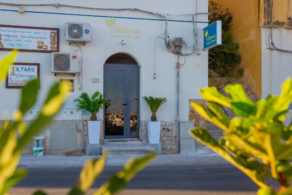 a white building with a blue door and plants at Vittoria Luxury Rooms in Sciacca