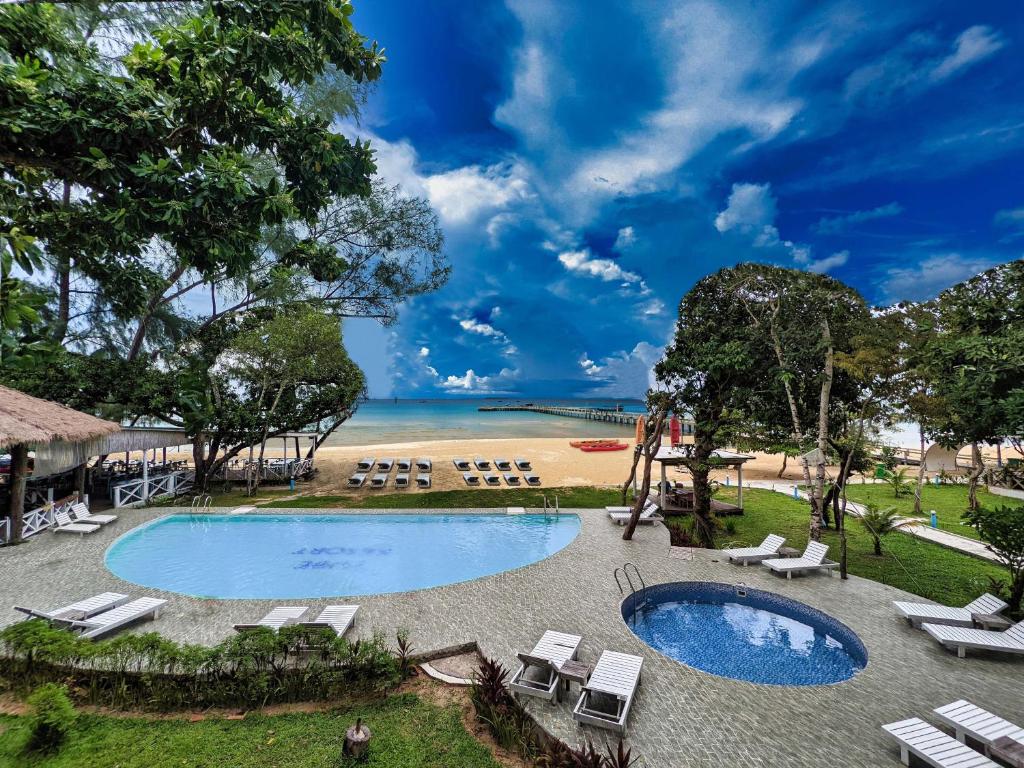 a pool with chairs and a beach in the background at Tube Resort in Koh Rong Sanloem