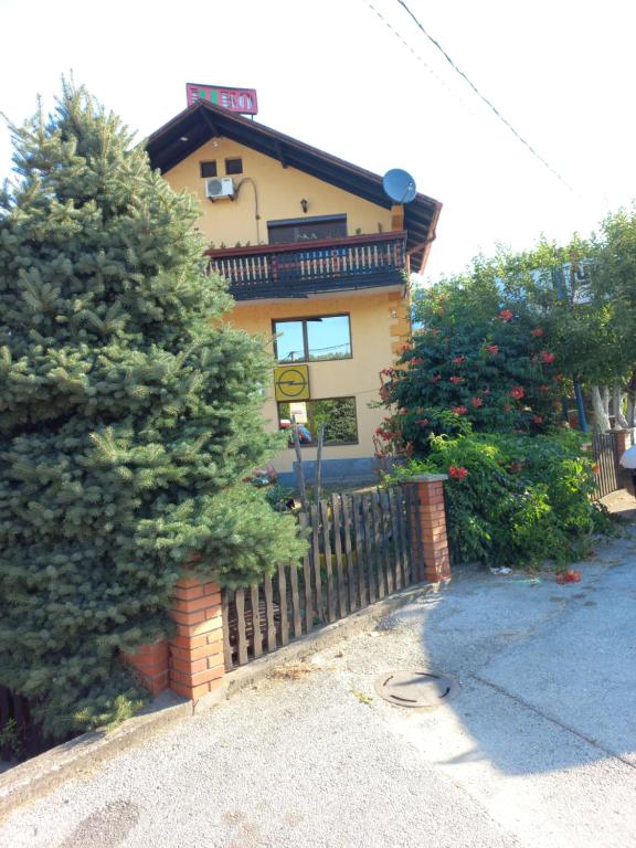a house with a fence and a tree in front of it at Apartments Emir in Tuzla