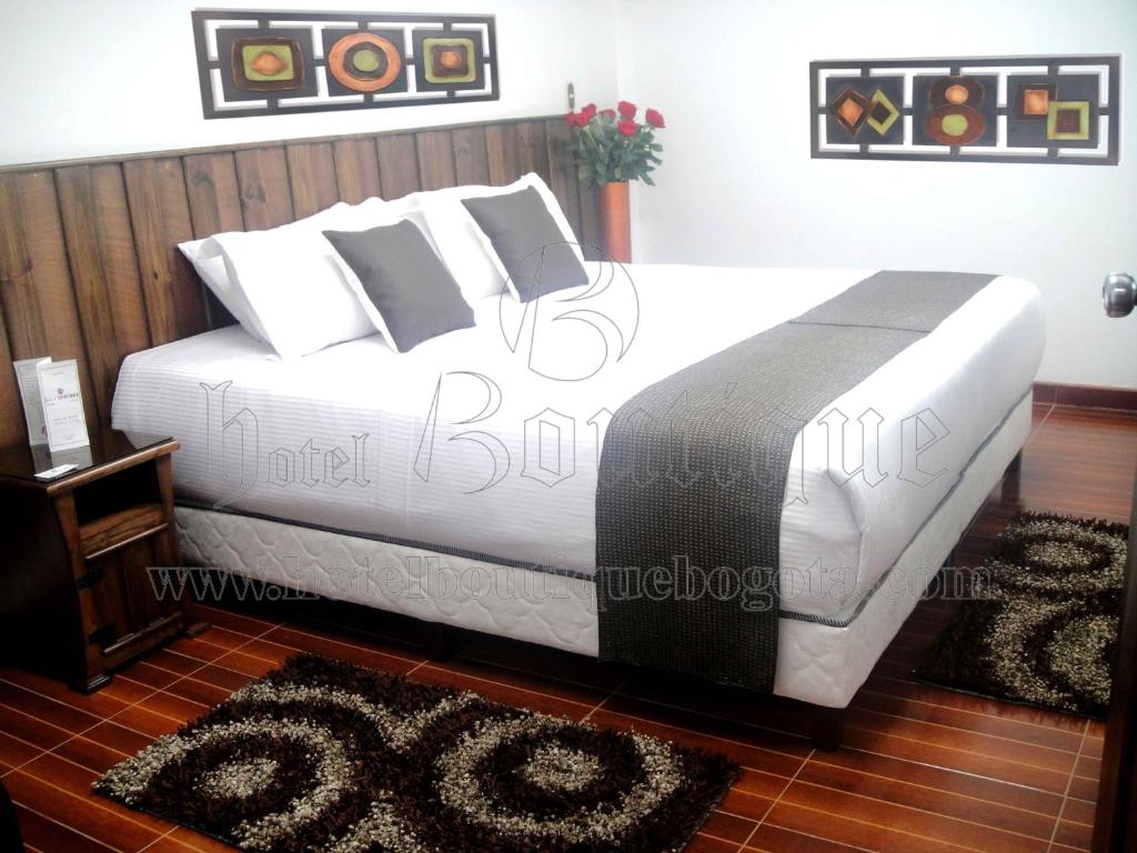 1 dormitorio con 1 cama grande con sábanas y almohadas blancas en Hotel Boutique Embajada de la Feria, en Bogotá