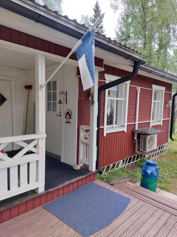una casa rossa con una bandiera sulla facciata di Ilmastoitu kesämökki Askolassa lähellä Porvoota a Askola