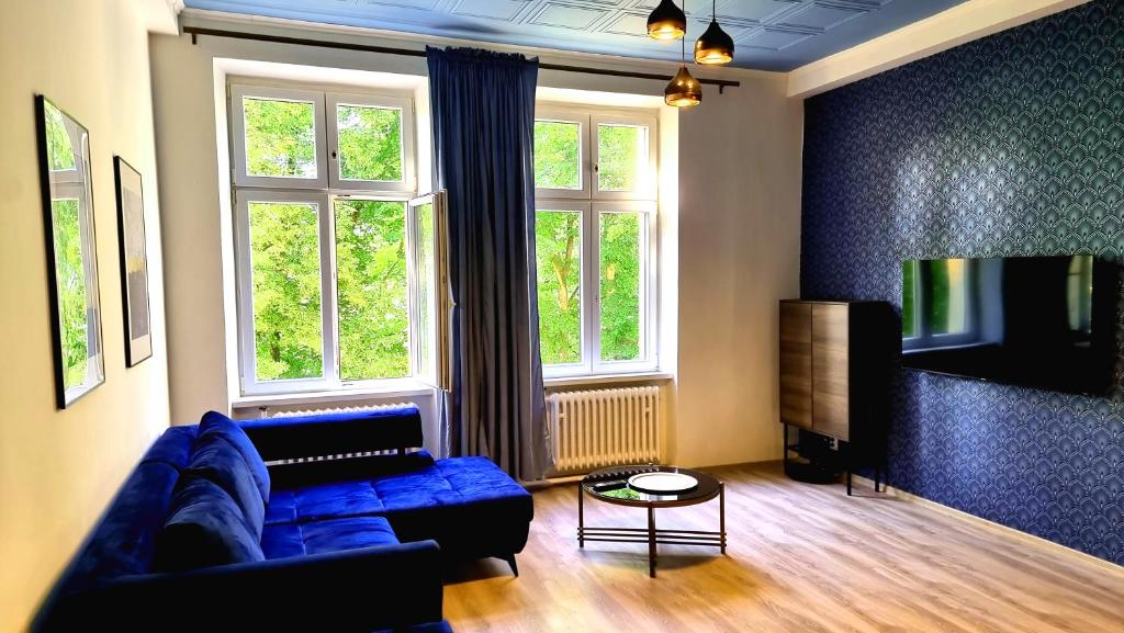 sala de estar con sofá azul y TV en Luxury Three-Bedroom Apartment en Teplice