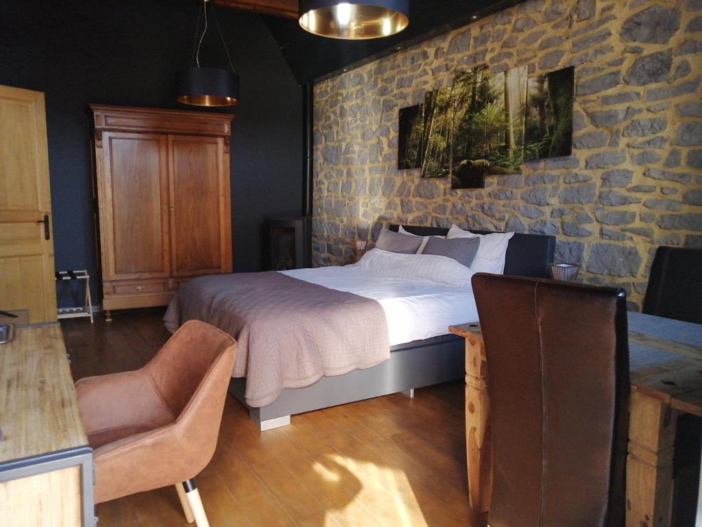 um quarto com uma cama e uma parede de pedra em La LAITERIE Ecaussinnes em Les Croisettes