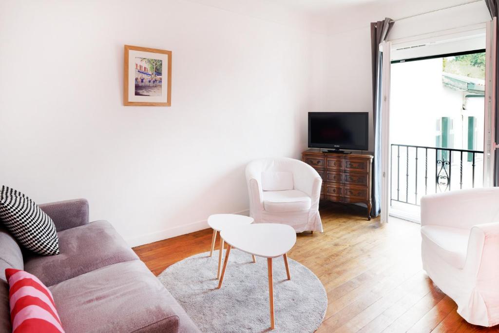 un salon avec un canapé et deux chaises et une télévision dans l'établissement Appartement Saint-jean-de-luz, à Saint-Jean-de-Luz