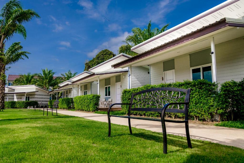 a park bench in the grass in front of a house at ONE Chumphon Hotel in Chumphon