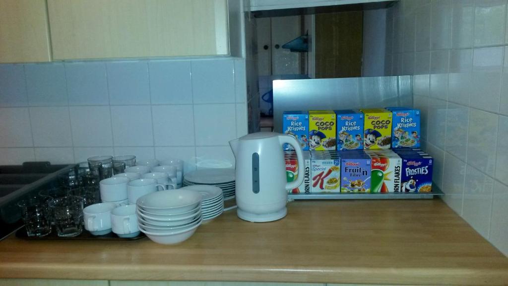 eine Arbeitsplatte mit Tassen und Tellern sowie eine Kaffeemaschine in der Unterkunft Cedars House Hotel in Croydon