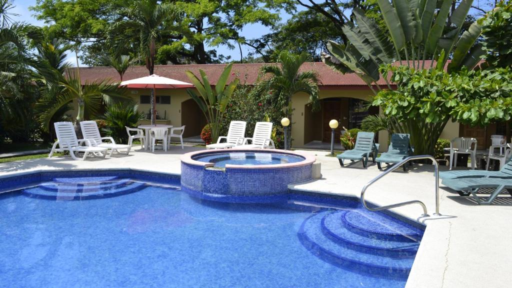 a pool with chairs and a table and a house at Villa Creole in Jacó