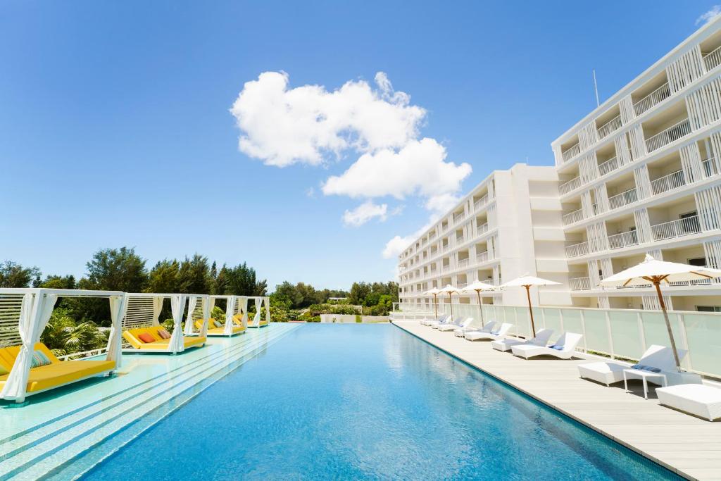 una piscina en un hotel con sillas y sombrillas en Hoshino Resorts BEB5 Okinawa Serakaki, en Onna