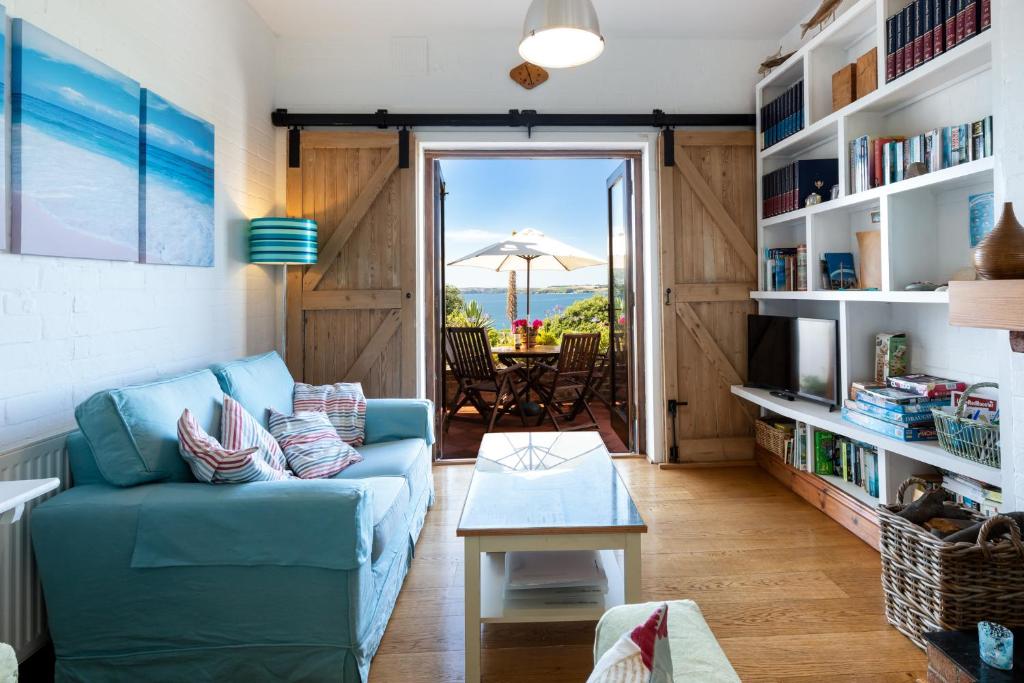 a living room with a blue couch and a table at The Old Coastguard Station - Bay Views & Pool Table in Falmouth