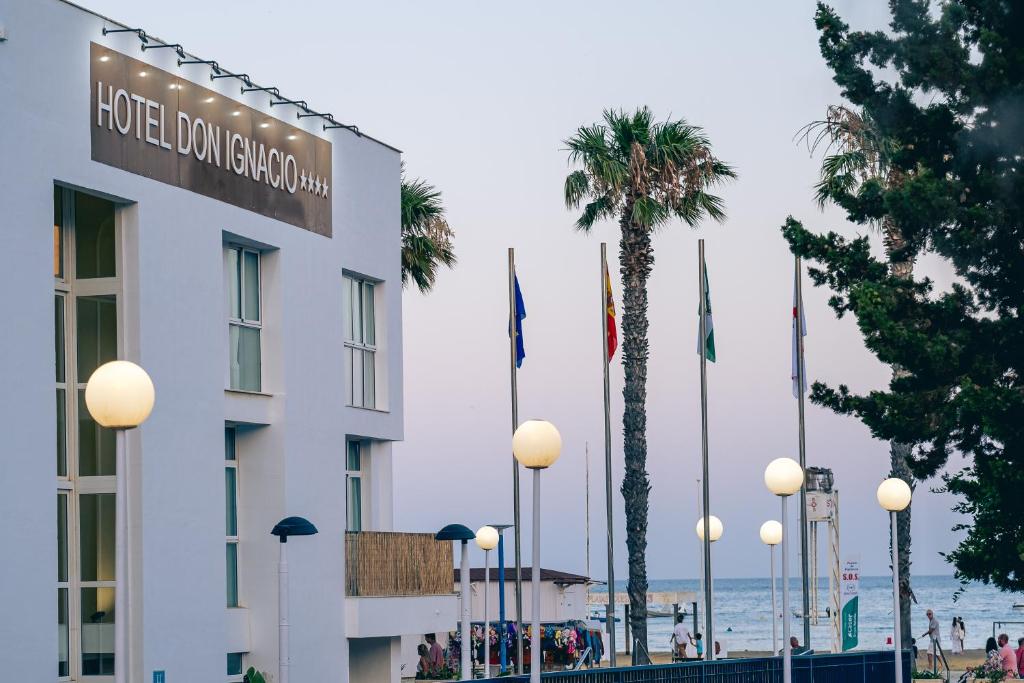 a hotel building with palm trees and the ocean at Hotel Don Ignacio in San José