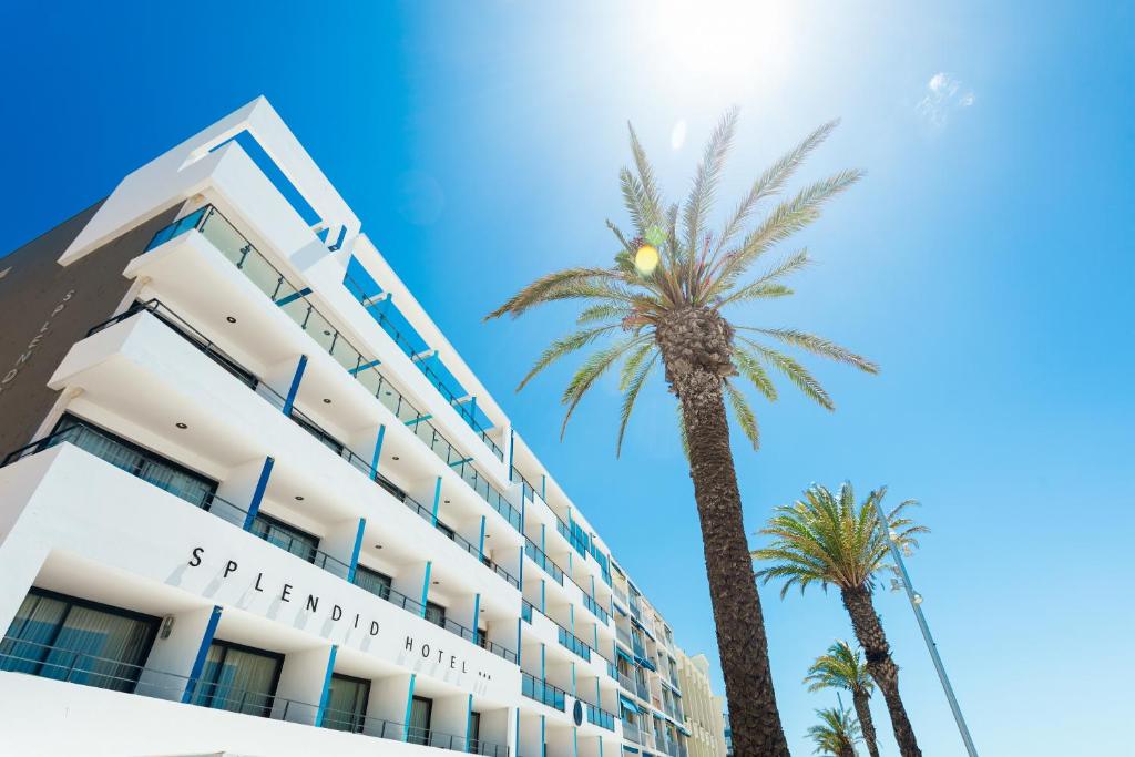 a hotel with palm trees in front of it at Hôtel Restaurant Splendid Camargue in Le Grau-du-Roi
