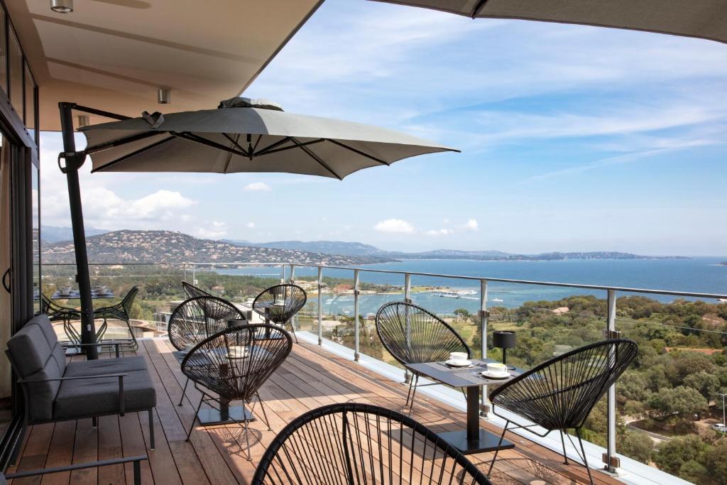 a balcony with chairs and a table and an umbrella at Hotel Alcyon in Porto-Vecchio