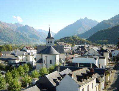 a small town with a church and mountains in the background at Luxury Guest House in the Centre of Argeles Gazost in Argelès-Gazost