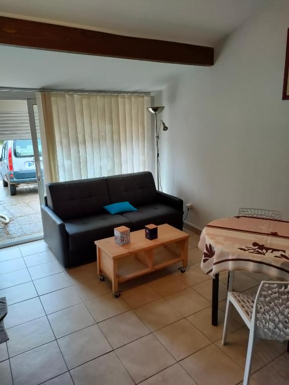 uma sala de estar com um sofá preto e uma mesa em CHEZ TINOU appartement T2 saisonnier em Florensac