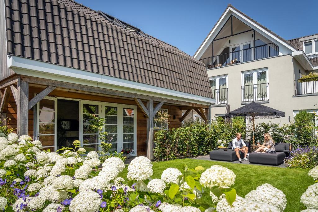 two people sitting on couches in the garden of a house at Just Texel Suites & Apartments in Den Burg