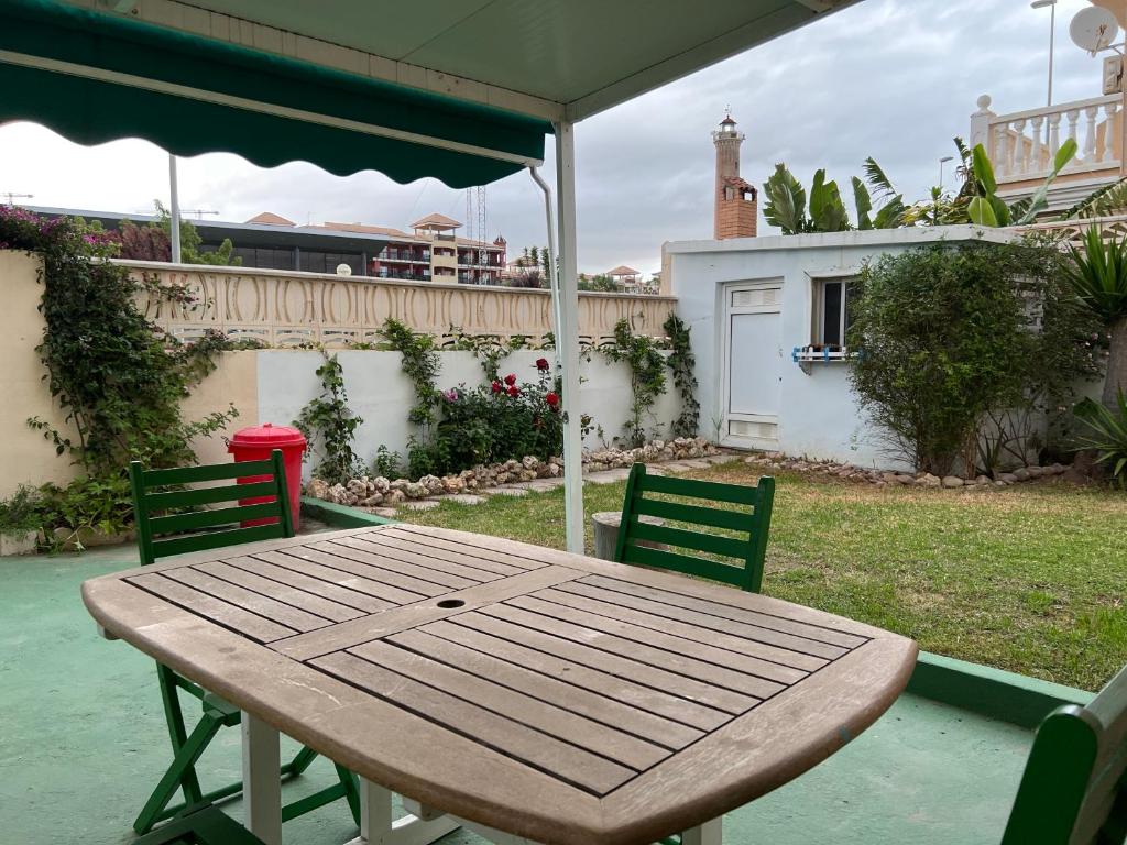 einen Holztisch mit zwei Stühlen und einem Sonnenschirm in der Unterkunft Apartamento con jardín Atalaya Canet in Canet d'en Berenguer