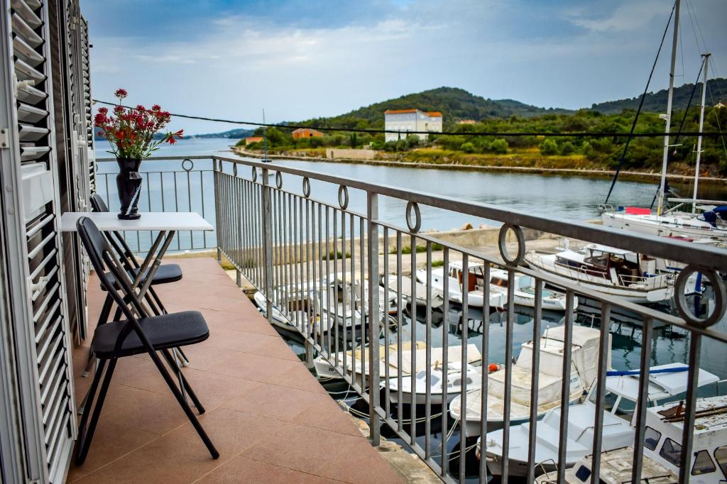 a balcony with chairs and a view of a river at Maslinčica in Veli Iž