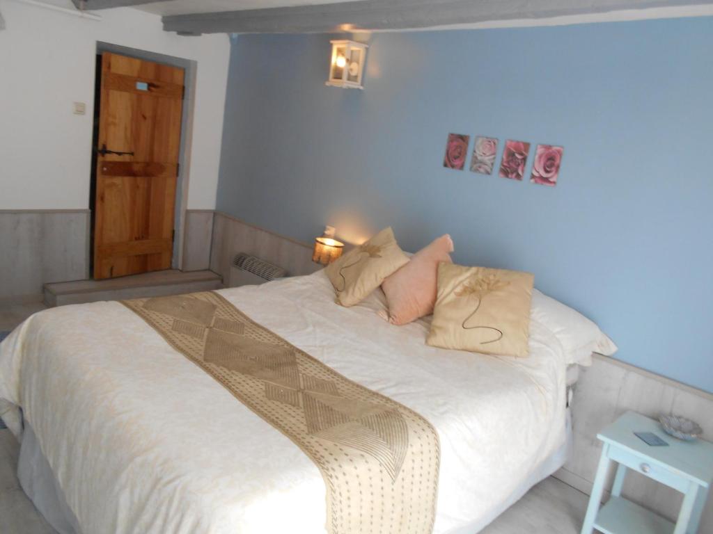 um quarto com uma cama com lençóis brancos e almofadas em Les Landes em Saint-Pardoux-Corbier