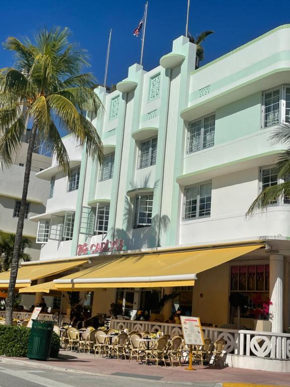 a hotel with tables and chairs in front of it at Beachfront Apt in Carlyle Hotel on Ocean Drive in Miami Beach
