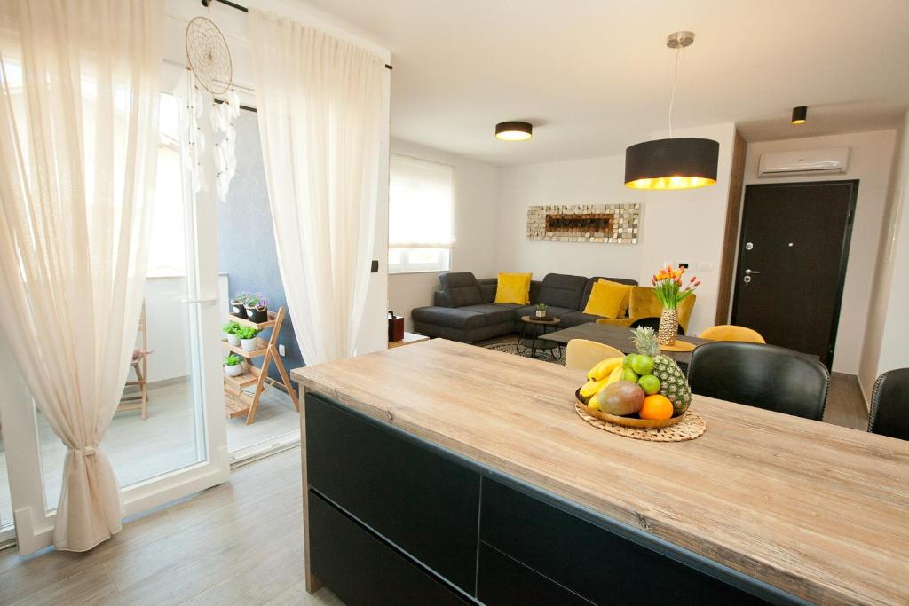a kitchen and living room with a table with a bowl of fruit at Luxury apartment Eva in Zadar