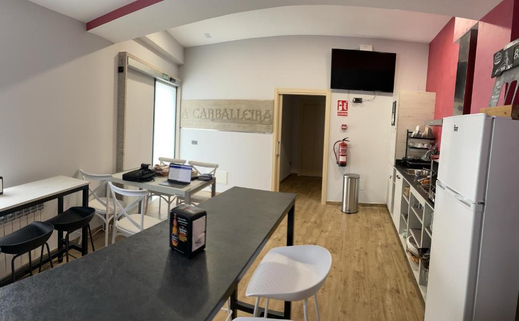 a kitchen with a table and chairs and a refrigerator at Albergue a Carballeira in Villalba