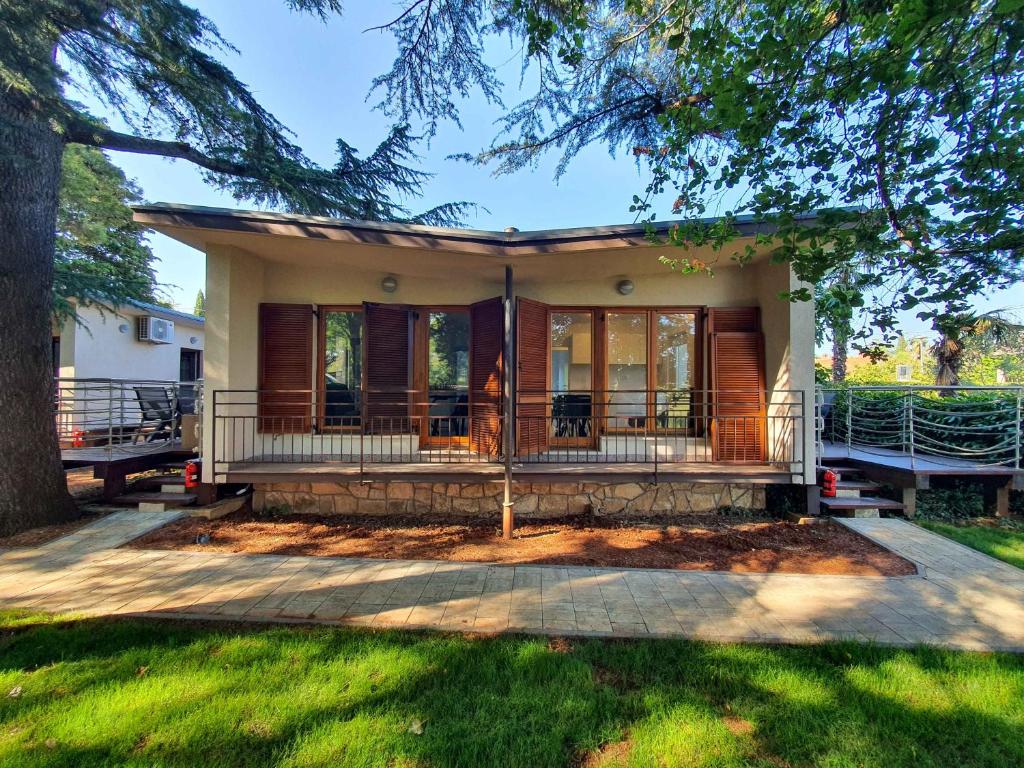 une maison avec une véranda et un arbre dans l'établissement Tisa Homes, à Savudrija