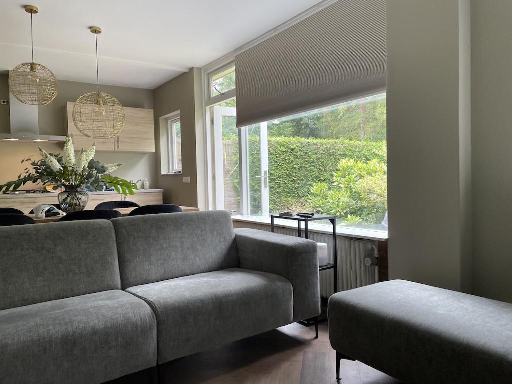 - un salon avec un canapé et une grande fenêtre dans l'établissement Comfortabel tot rust komen in het Veluwse bos, à Otterlo