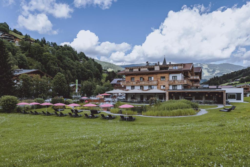 a group of tables and umbrellas in front of a building at Ski & Bike Hotel Wiesenegg in Saalbach Hinterglemm