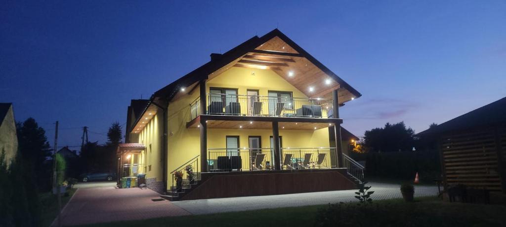 Una gran casa amarilla con balcón por la noche en Ojcowski Las, en Biały Kościół