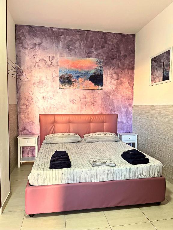ein Schlafzimmer mit einem Bett und einer rosa Wand in der Unterkunft Monolocale Viola - A casa di Ludovica e Martina in Gallipoli