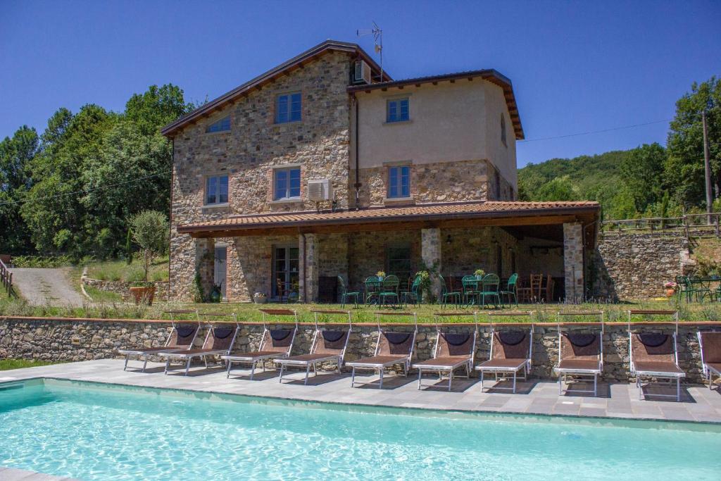 une maison avec des chaises et une piscine en face de celle-ci dans l'établissement Agriturismo I Giunchi, à Mochignano