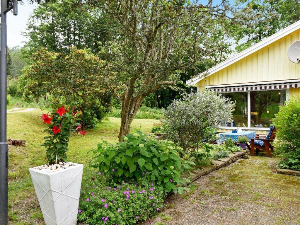 un jardín con flores y una casa con un árbol en 4 person holiday home in LYSEKIL en Brastad